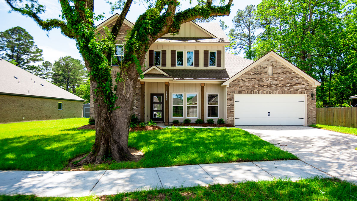 dual-story home with brown brick and tan hardi siding with brown front door and shutters with two-car garage