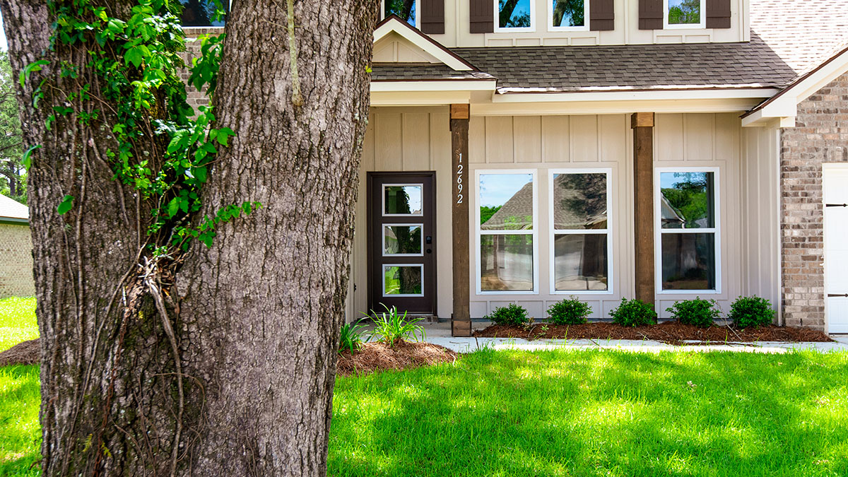 dual-story home with brown brick and tan hardi siding with brown front door and shutters with two-car garage