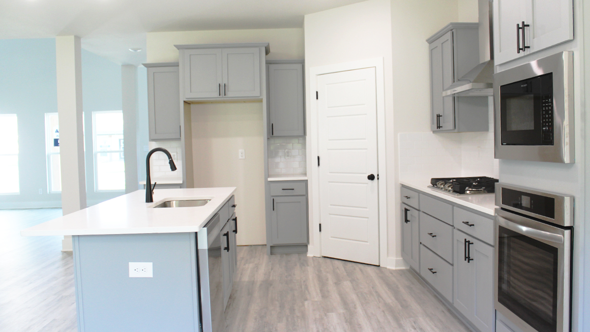 Grey kitchen cabinets and white quartz countertops with stainless steel appliances