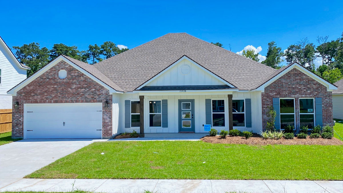 single-story home with red brick and light gray hardie siding and blue front door and shutters with porch and two-car garage