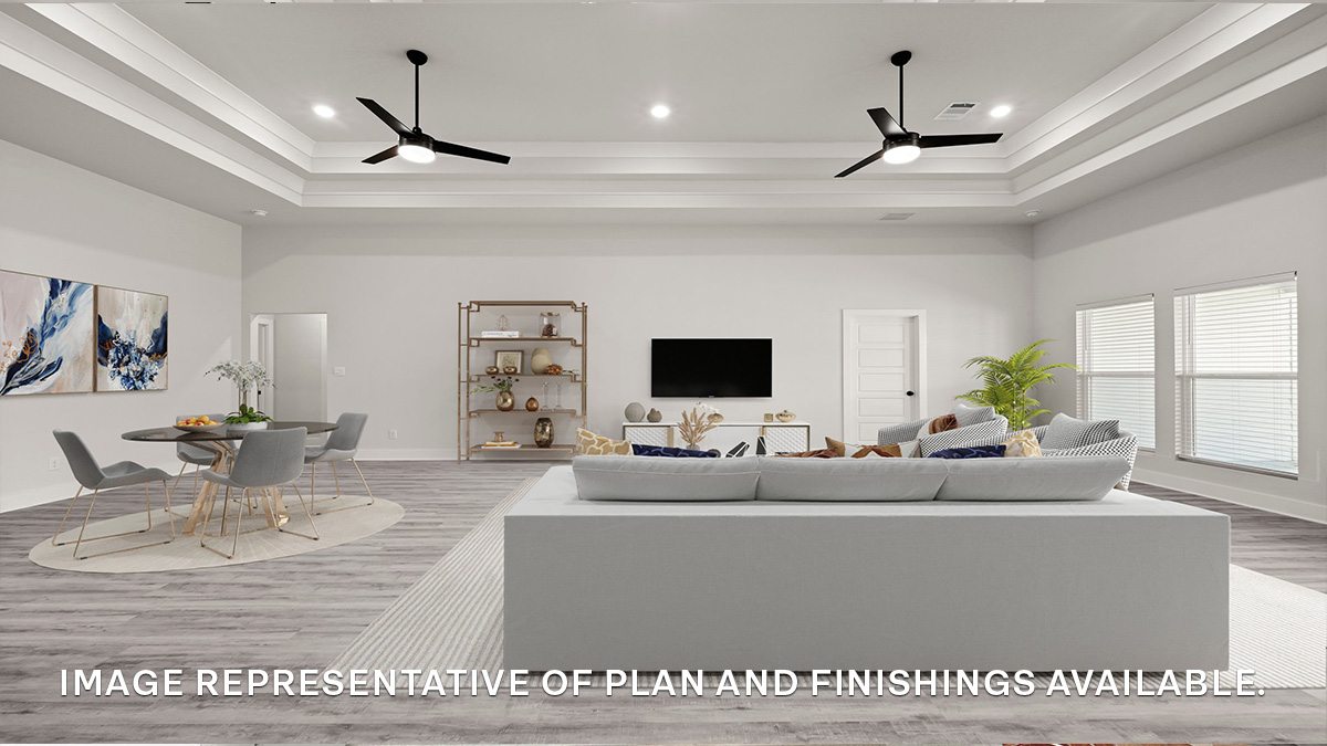 Open-concept living room with vaulted high ceilings with windows overlooking backyard