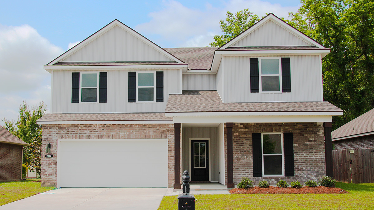 dual-ctoru home with tan brick and light vinyl siding with black front door and shutters with porch and two-car garage