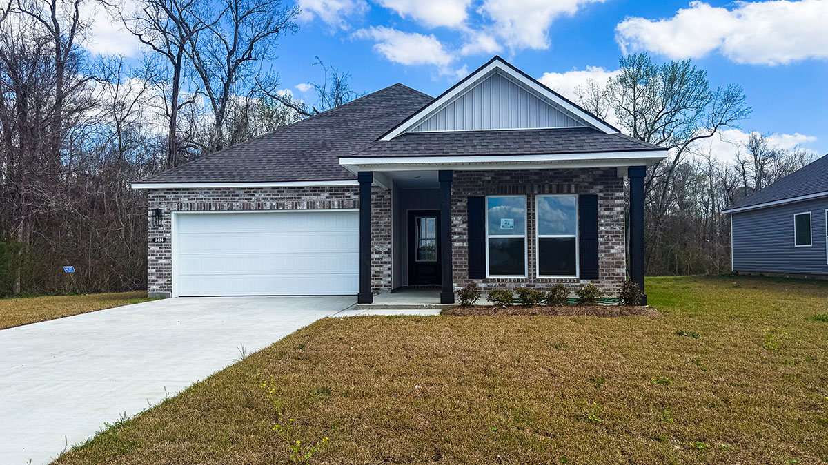 single-story home with gray brick and light gray vinyl siding with black front door and shutters and porch with two-car garage