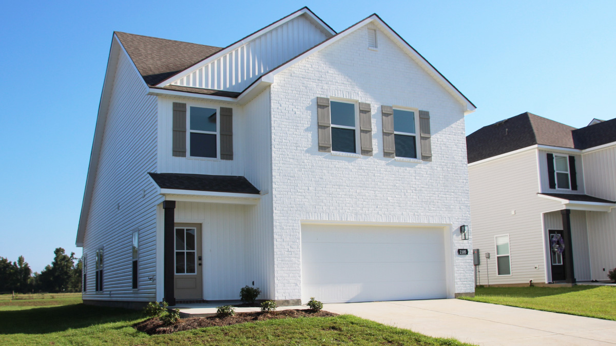 Two-story home with white hardie vinyl and white brick. Tan glass front door with tan shutters and white trim.