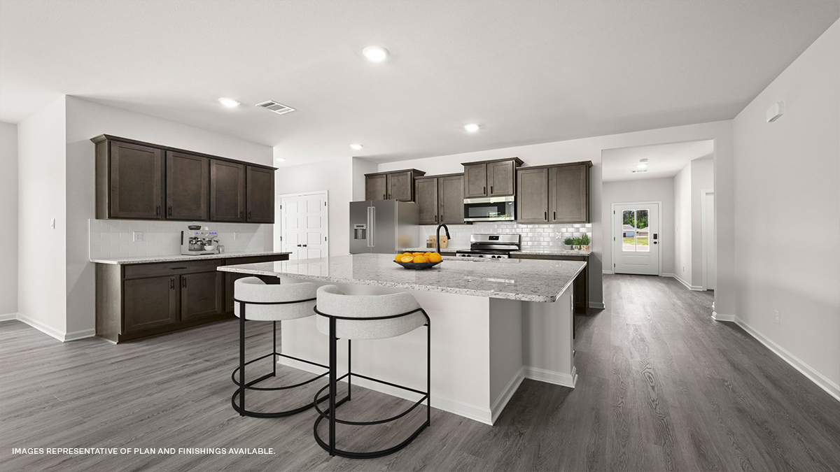 dark kitchen island with stainless steel appliances, pantry and foyer leading to front of home