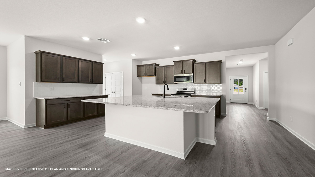 dark kitchen island with stainless steel appliances, pantry and foyer leading to front of home