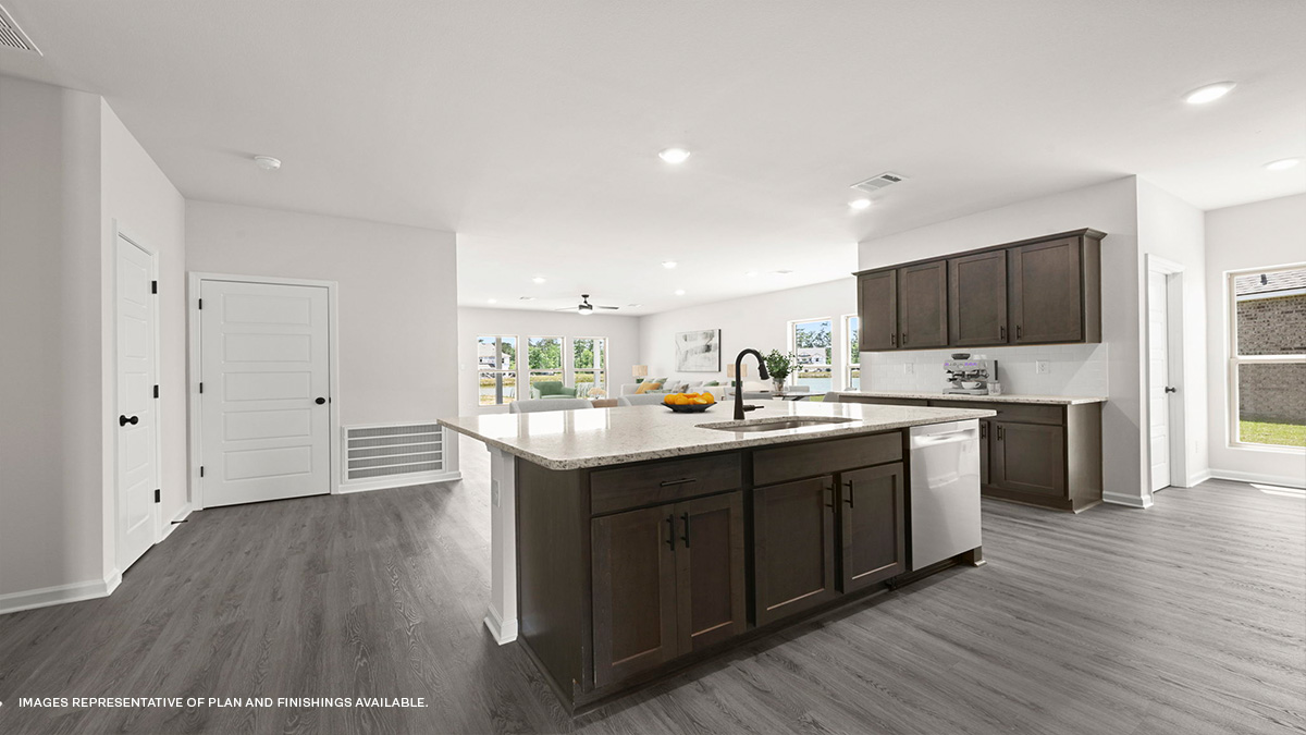 dark kitchen island with stainless steel appliances and open-concept living space in the rear