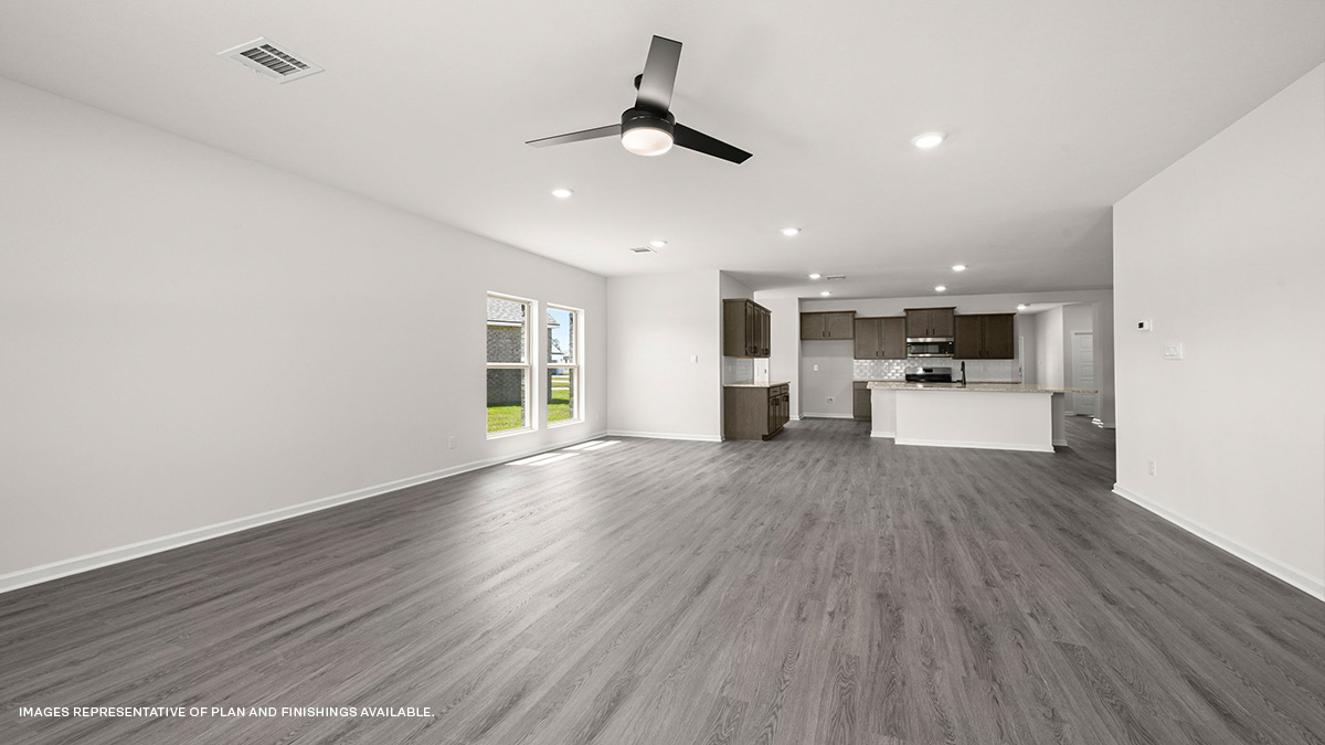 living and dining area with kitchen area in the rear with dark kitchen cabinets and fan
