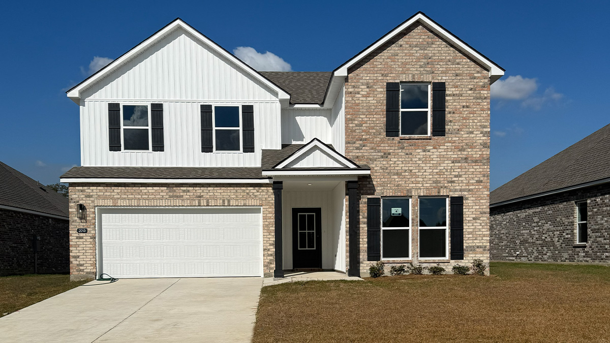 double-story home with tan brick and white vinyl siding with black front door and shutters with two-car garage