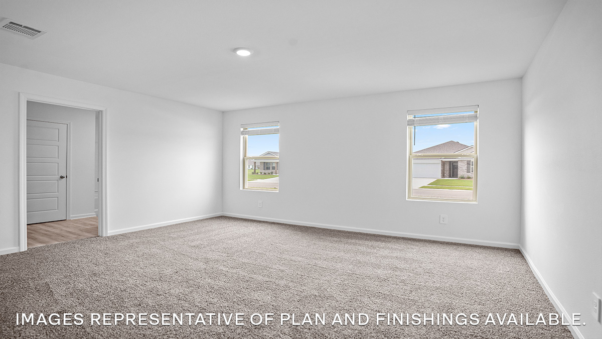 Large primary bedroom with dual windows overlooking the backyard