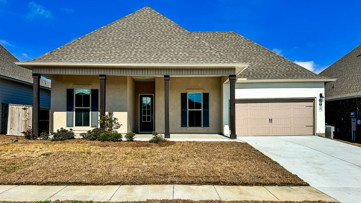 single-story home with tan stucco and white brick with green shutters and two-car garage