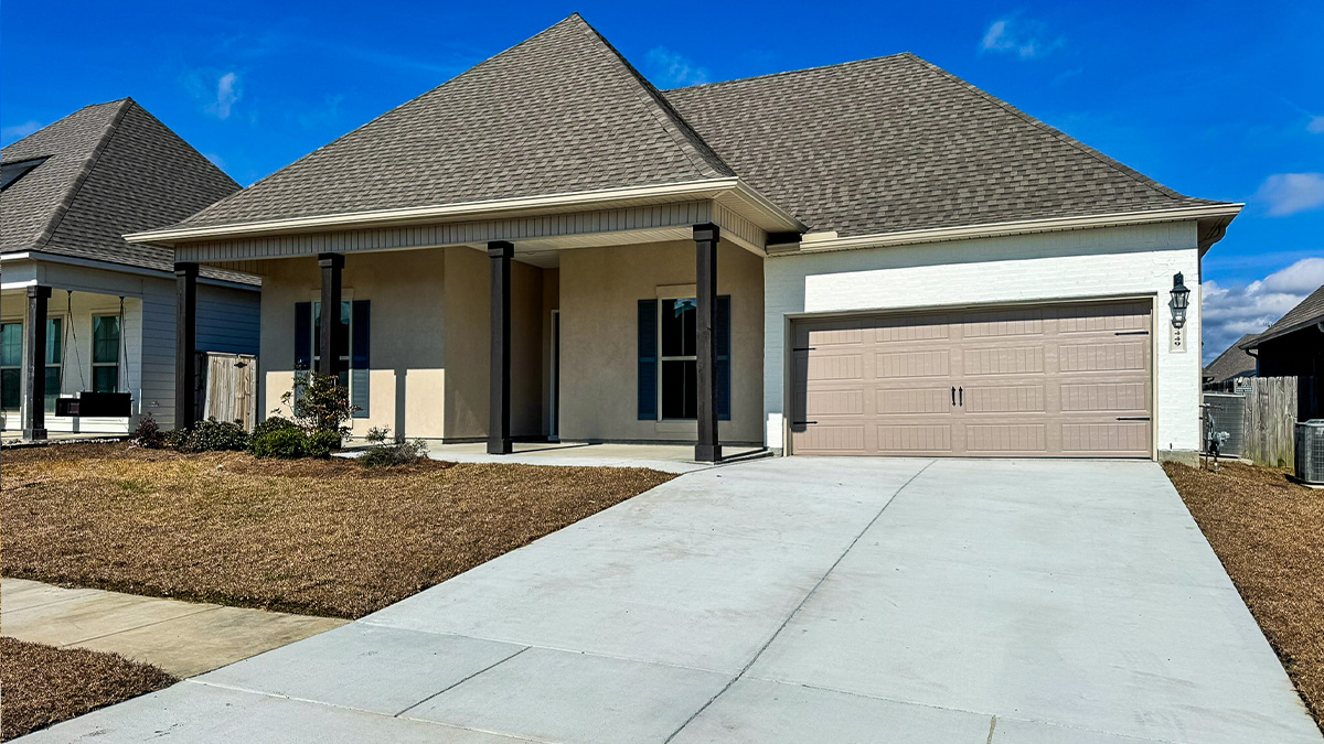 single-story home with tan stucco and white brick with green shutters and two-car garage