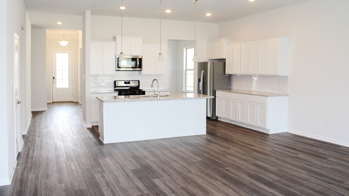 Open concept living room and White kitchen cabinets with stainless steel appliances and eat in kitchen space