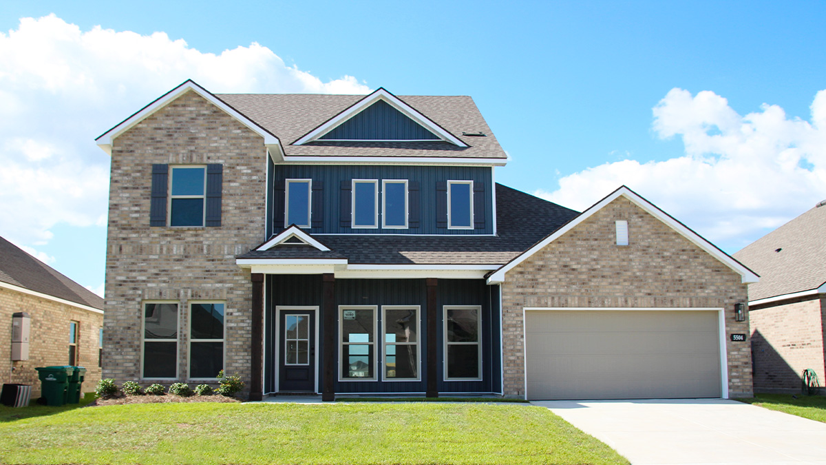 Two-story home with white hardie vinyl and brown brick. Black glass front door with black shutters and white trim.