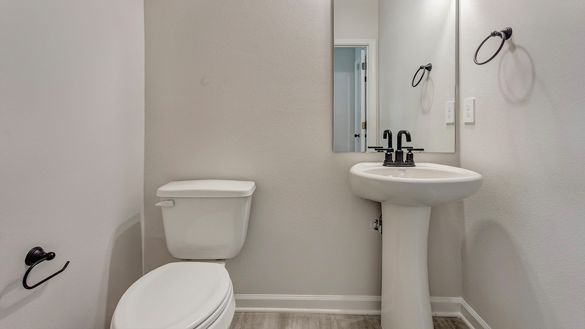 Downstairs half bath with pedestal sink and toilet