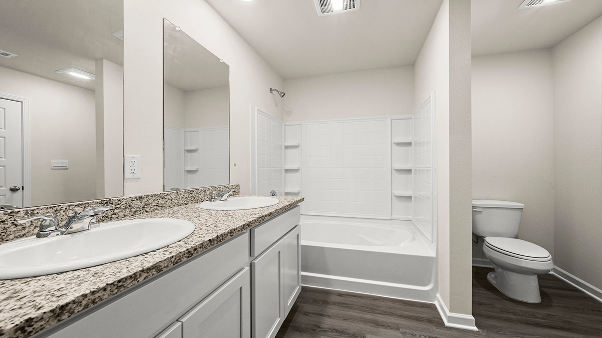 White dual vanities with shower and tub combo and toilet