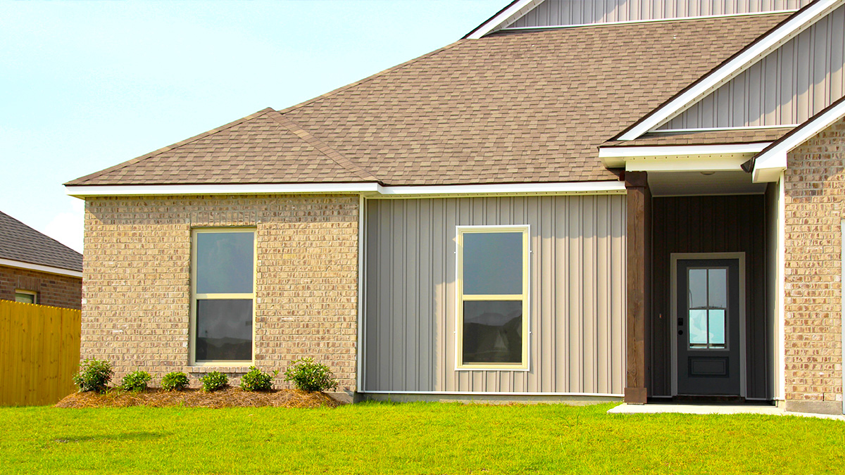 Single-story home with tan brick and tan hardie vinyl. Black glass front door and white two car garage.