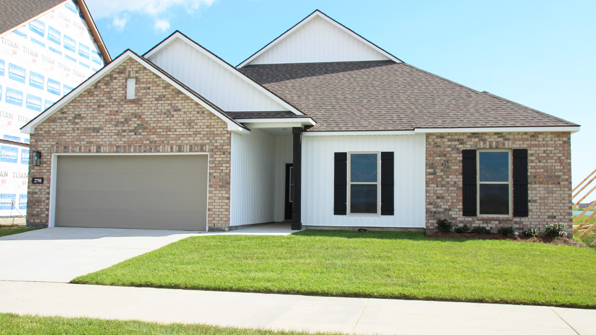 Single-story home with brown brick. Black glass front door with black shutters and white trim.