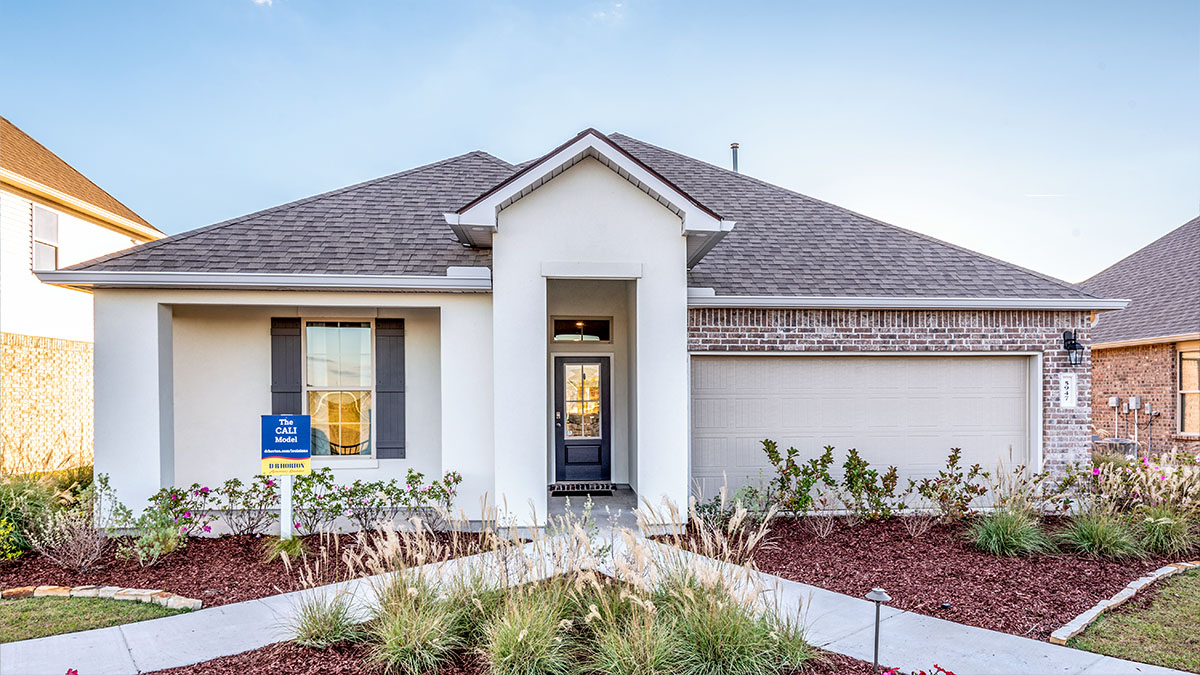 single-story home with tanstucco siding with black front door and shutters with two-car garage