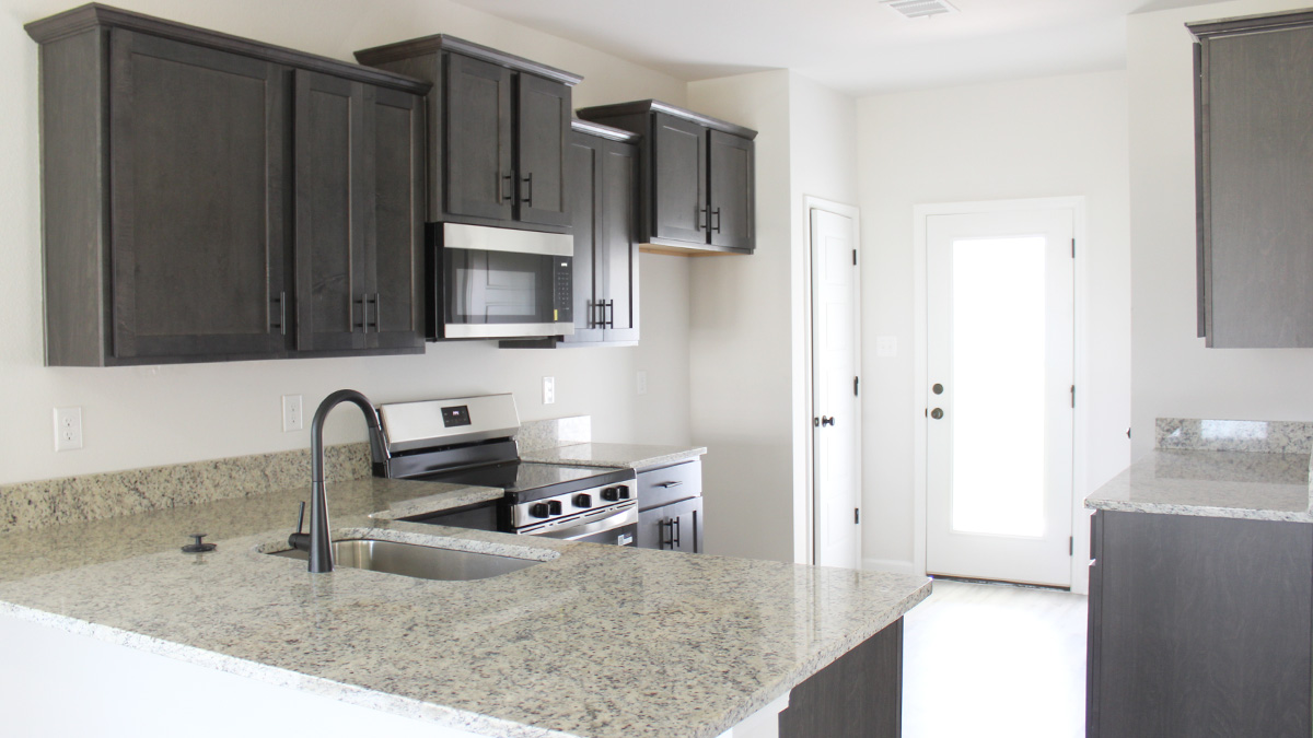 Dark kitchen cabinets with stainless steel appliances and eat in kitchen space