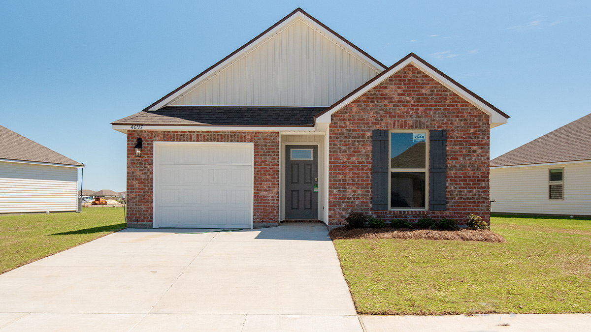 single-story home with red brick and tan vinyl siding with dark grey front door and shutters with one-car garage