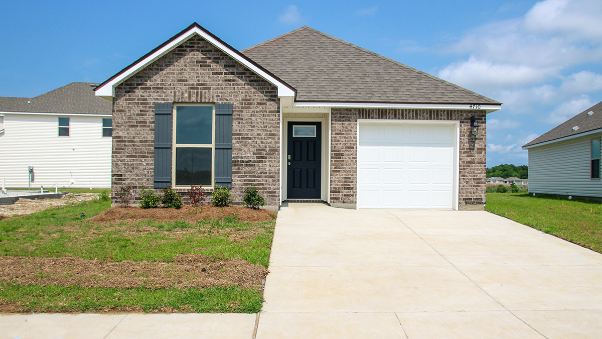 single-story home with tan brick and blue front door and shutters with one-car garage