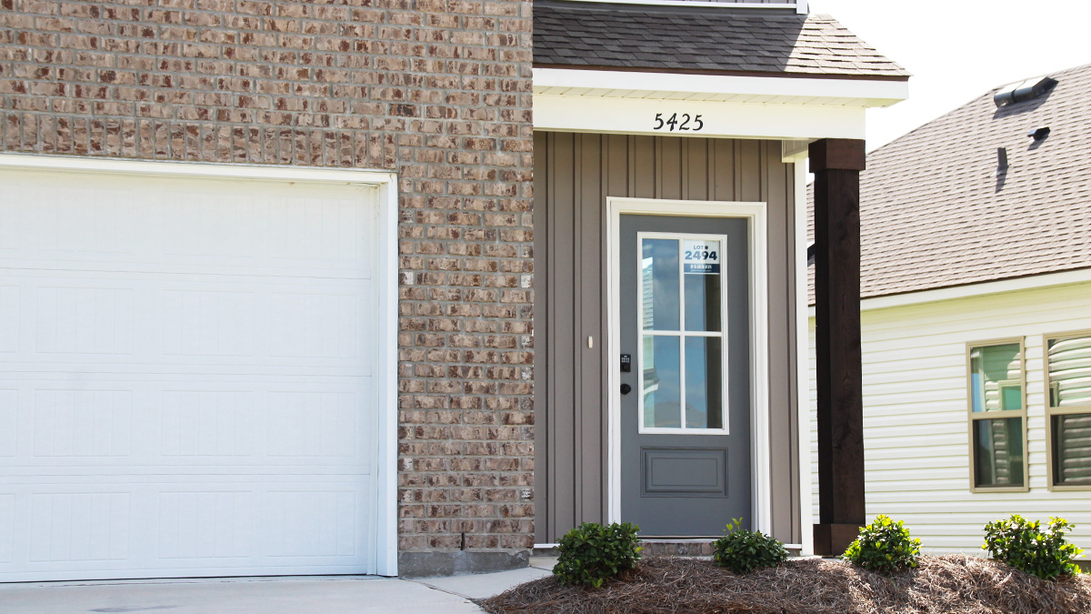 Two-story home with blue hardie vinyl and brown brick. Blue glass front door with blue shutters and white trim.