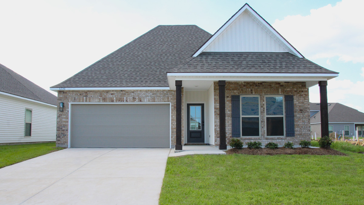 Single-story home with brown brick. Dark grey glass front door with dark grey shutters and white trim.