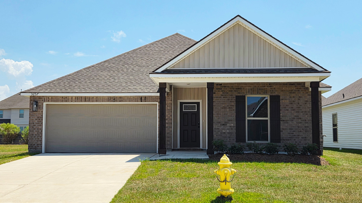Single-story home with brown brick. Black glass front door with black shutters and white trim.
