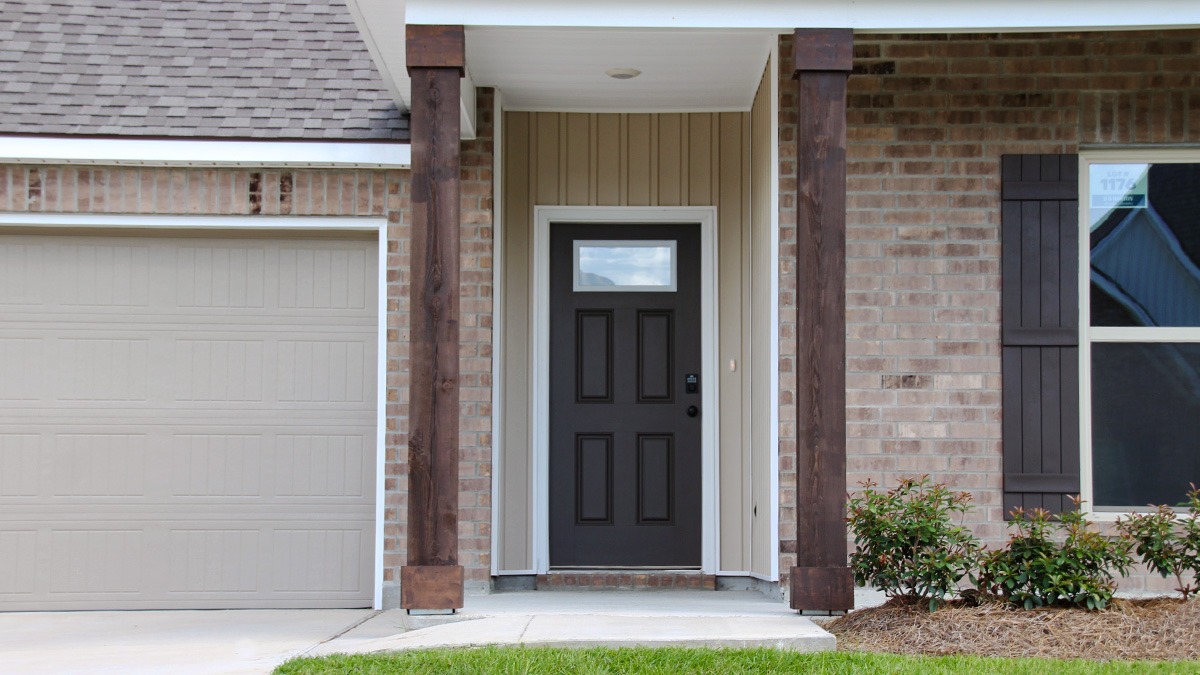 Single-story home with brown brick. Black glass front door with black shutters and white trim.