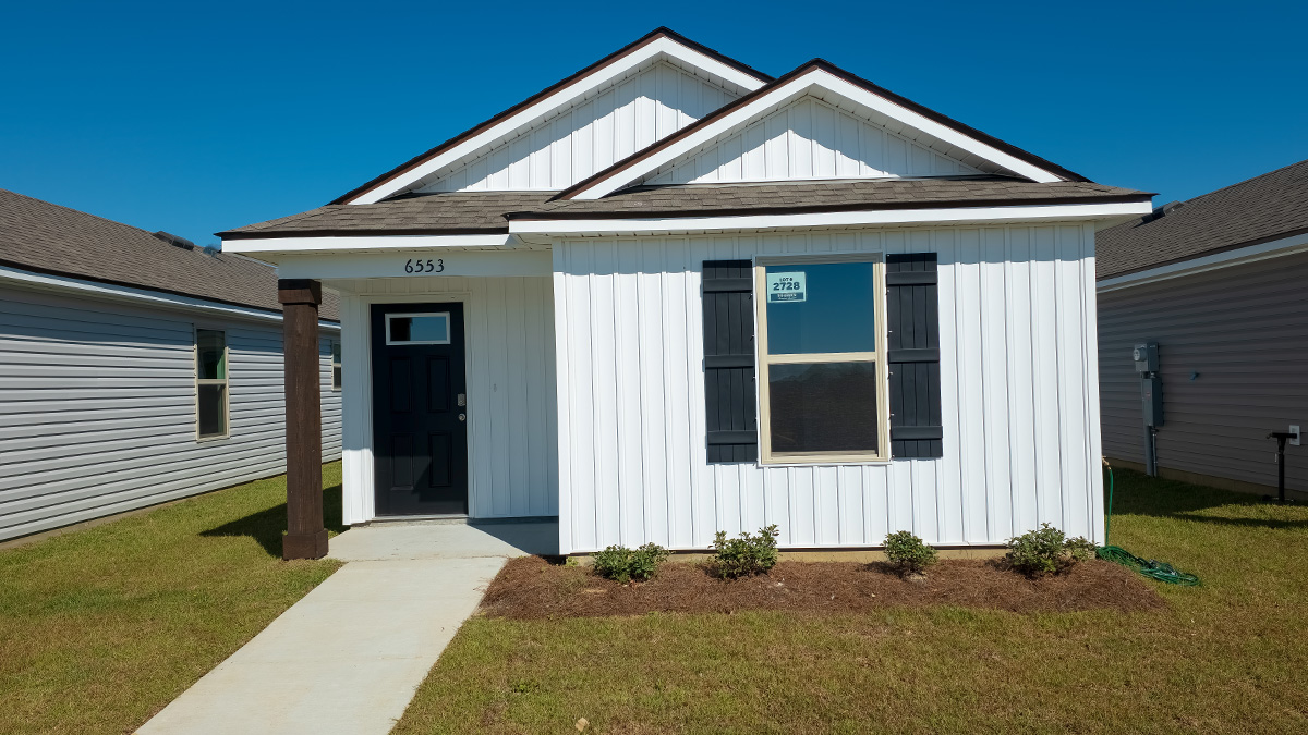 single-story home with white vinyl siding and black front door and shutters