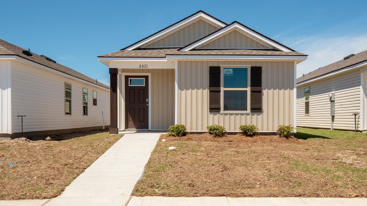 single-story home with tan vinyl siding with brown front door and shutters