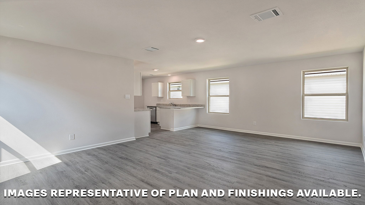 Open concept living space with dual windows looking into the yard with the kitchen nearby