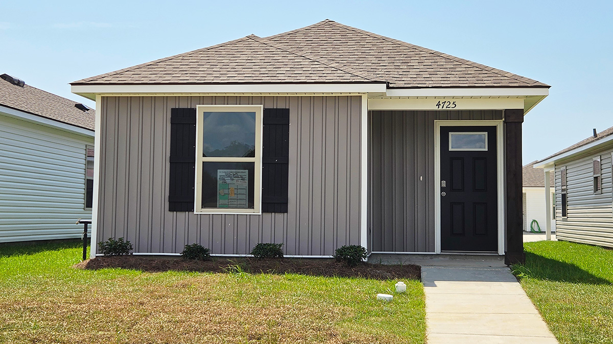 Single-story home with brown vinyl. Black glass front door with black shutters and white trim.