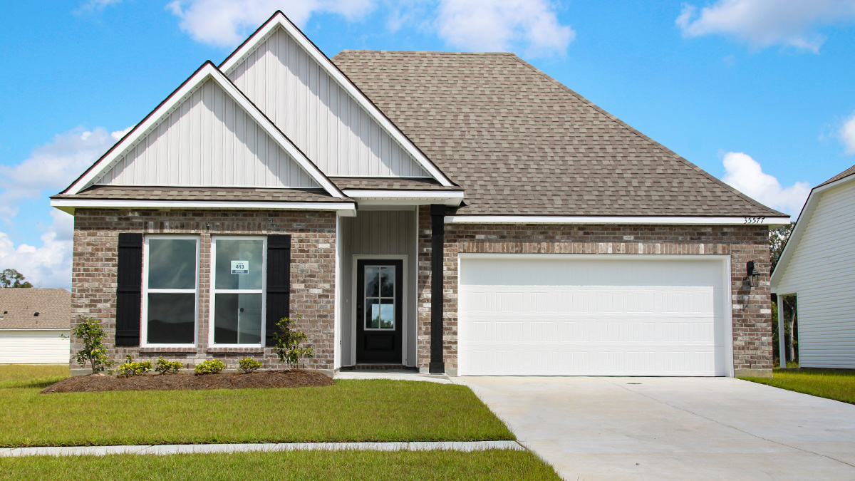 Single-story home with brown brick. Black glass front door with black shutters and white trim.