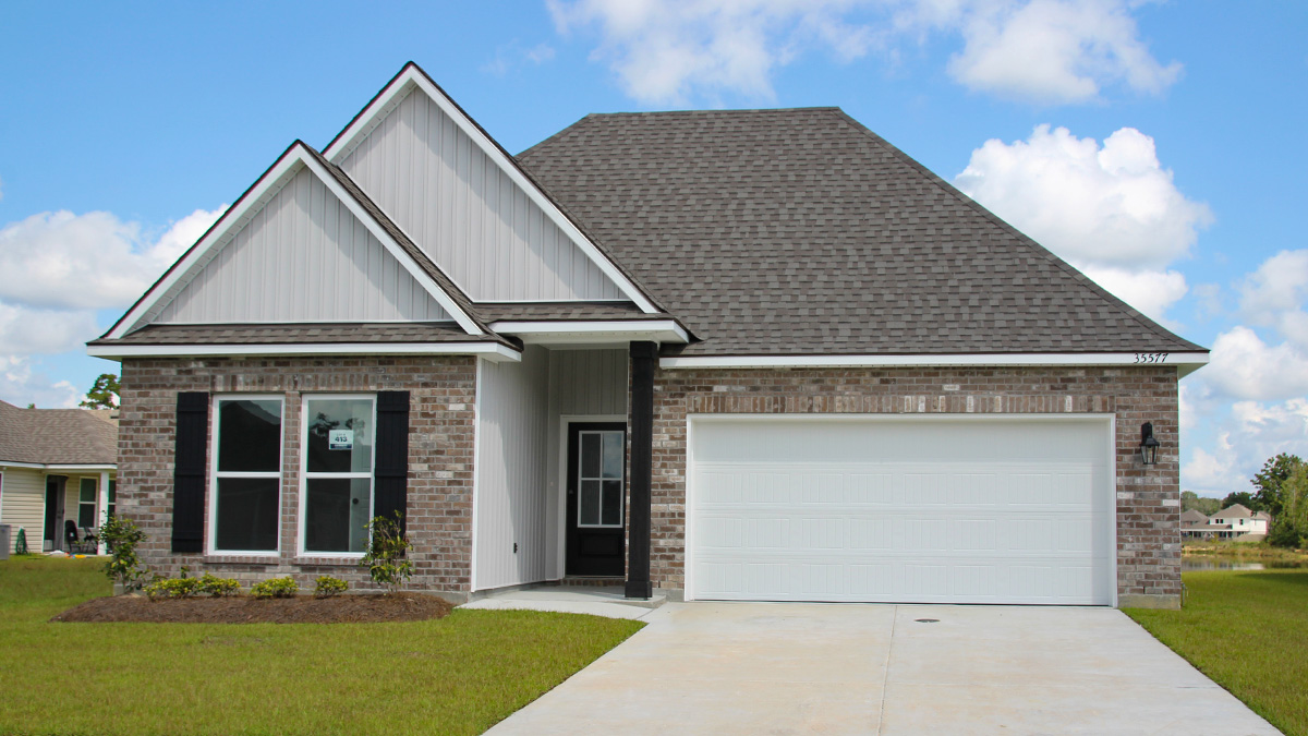 Single-story home with brown brick. Black glass front door with black shutters and white trim.