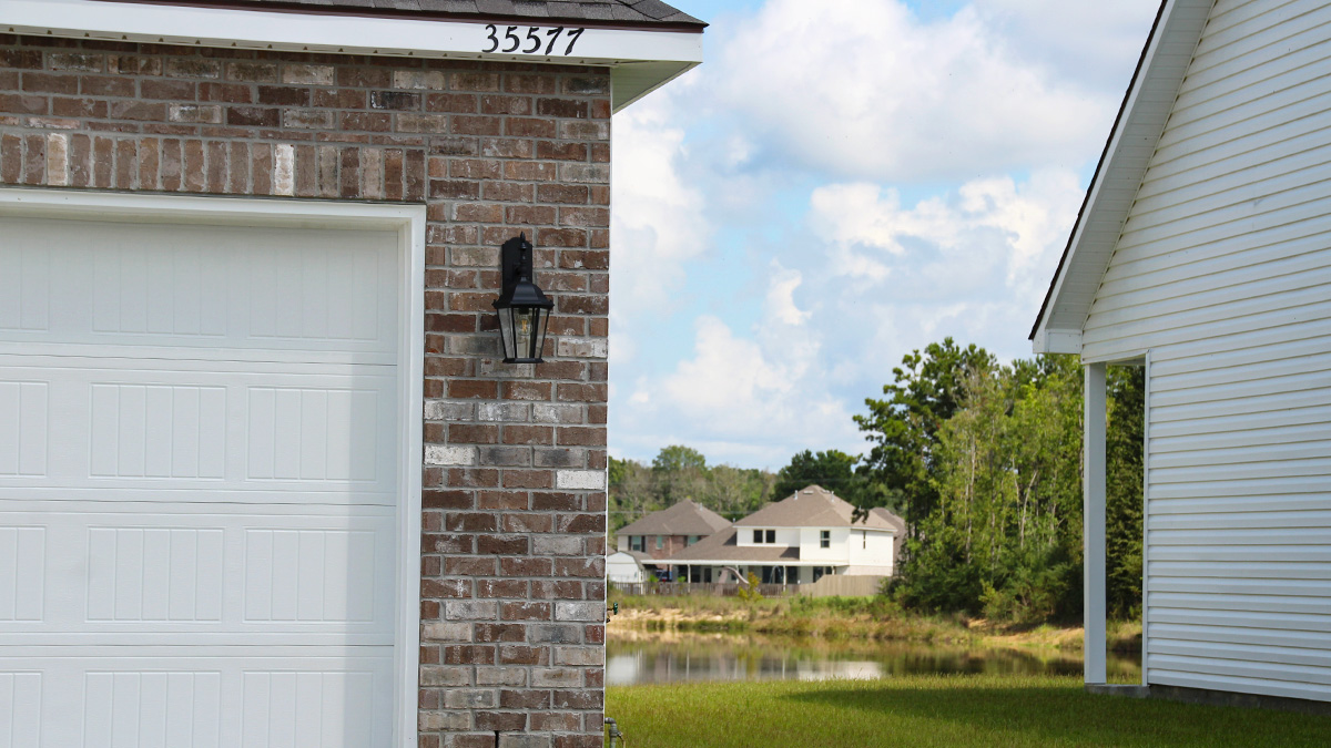Single-story home with brown brick. Black glass front door with black shutters and white trim.