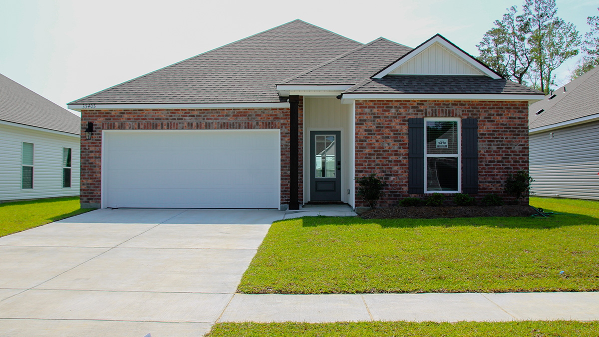 single-story home with red brick and tan vinyl siding with black front door and shutters with two-car garage