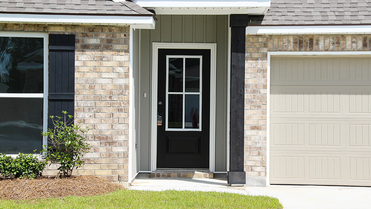 Single-story home with brown brick. Black glass front door with black shutters and white trim.
