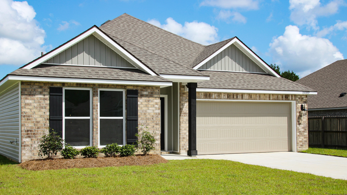 Single-story home with brown brick. Black glass front door with black shutters and white trim.