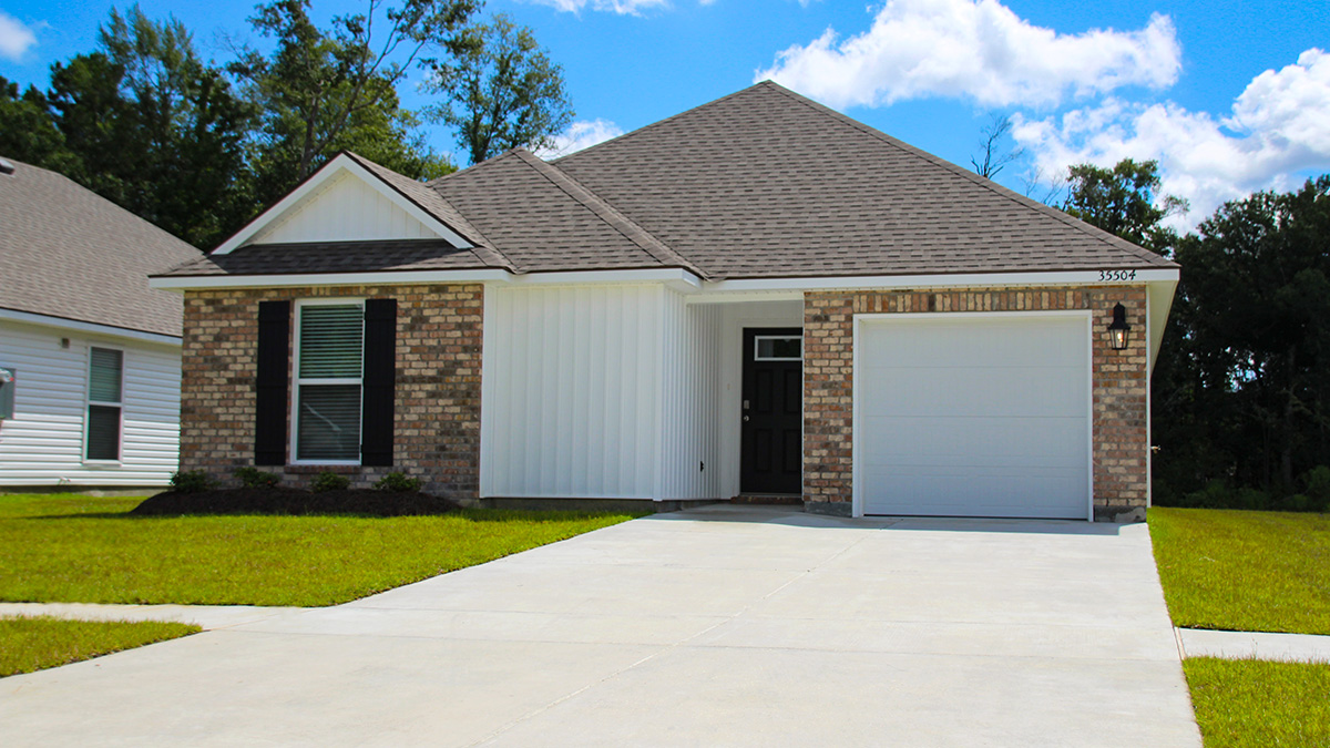 Single-story home with tan brick. Black glass front door with black shutters and white trim.