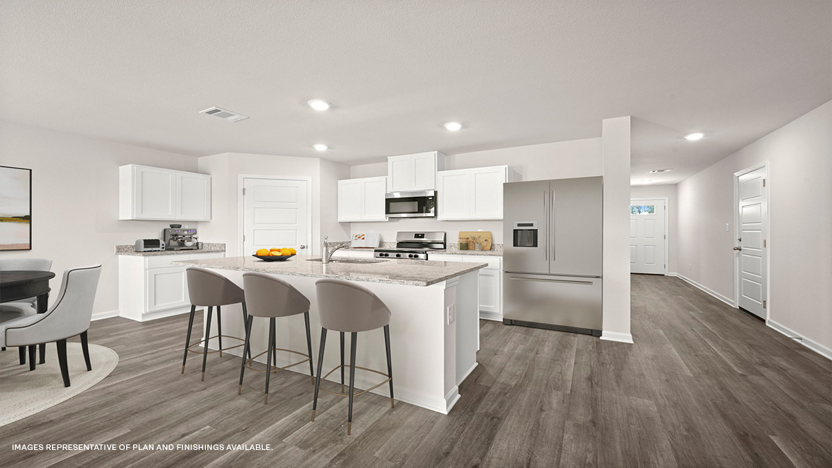 White kitchen island with stools and stainless-steel appliances with foyer and pantry