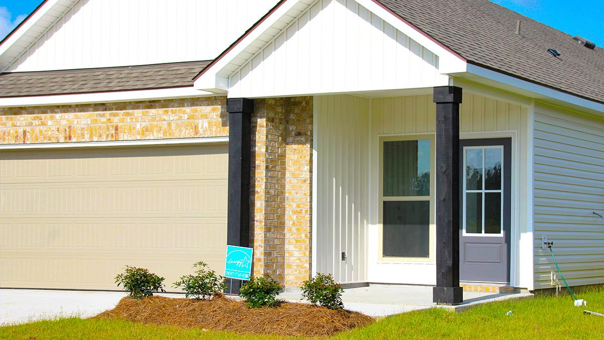 Single-story home with brown brick. Blue glass front door and two car garage.