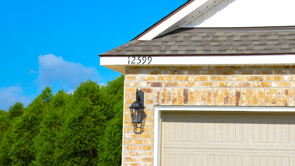 Single-story home with brown brick. Blue glass front door and two car garage.