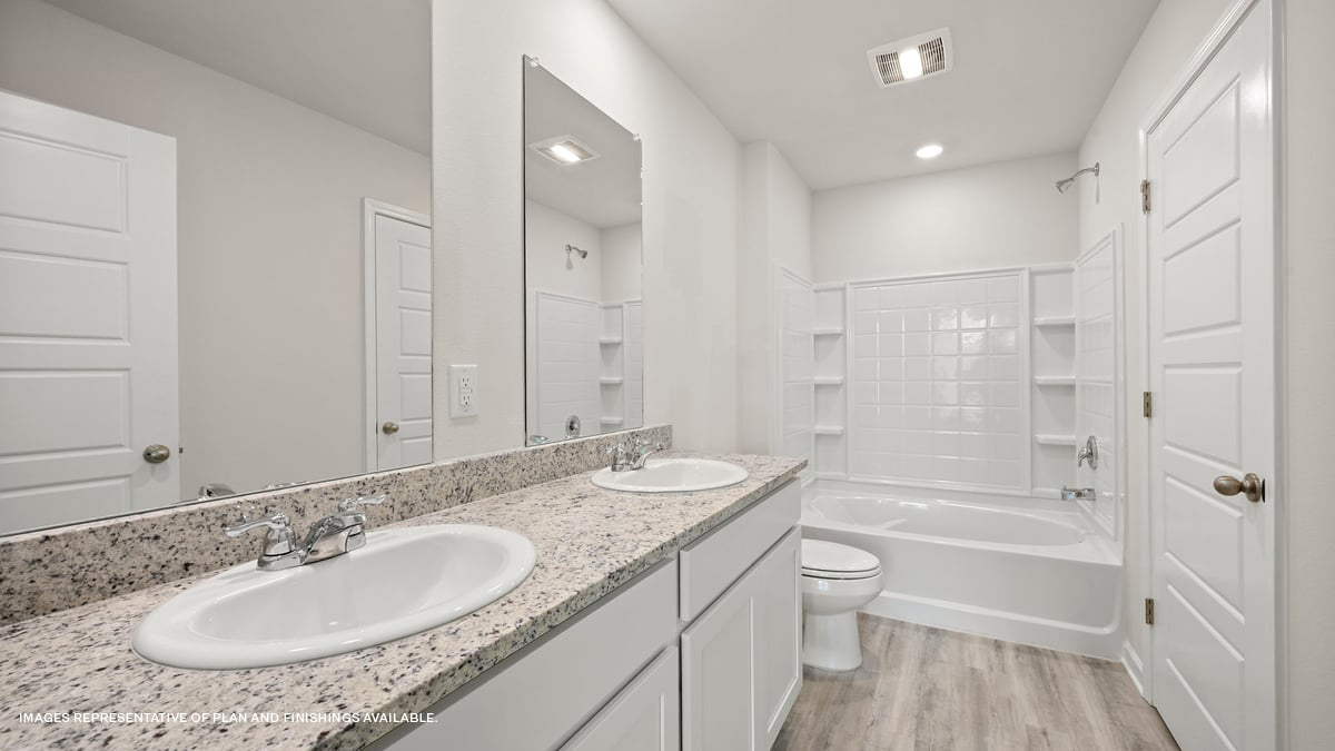 primary bathroom with dual vanities, mirror and shower tub combo