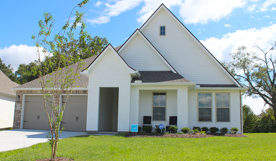 Single-story home with white hardie vinyl and brown brick. Black glass front door. and white trim.