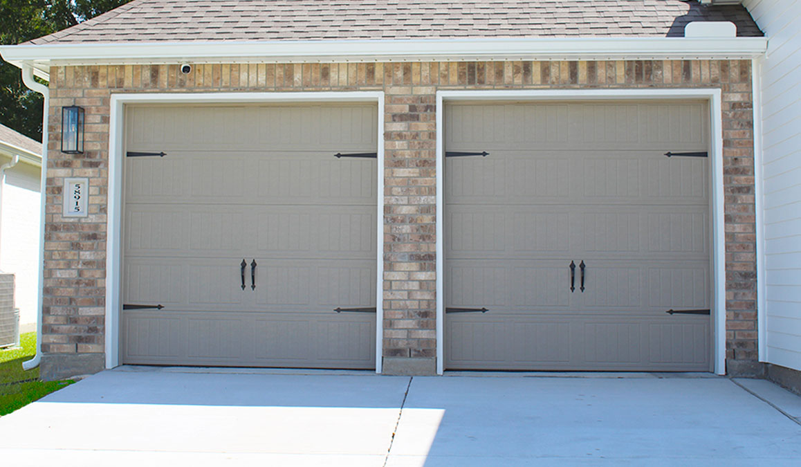Single-story home with tan vinyl and brown brick. Black glass front door. and white trim.