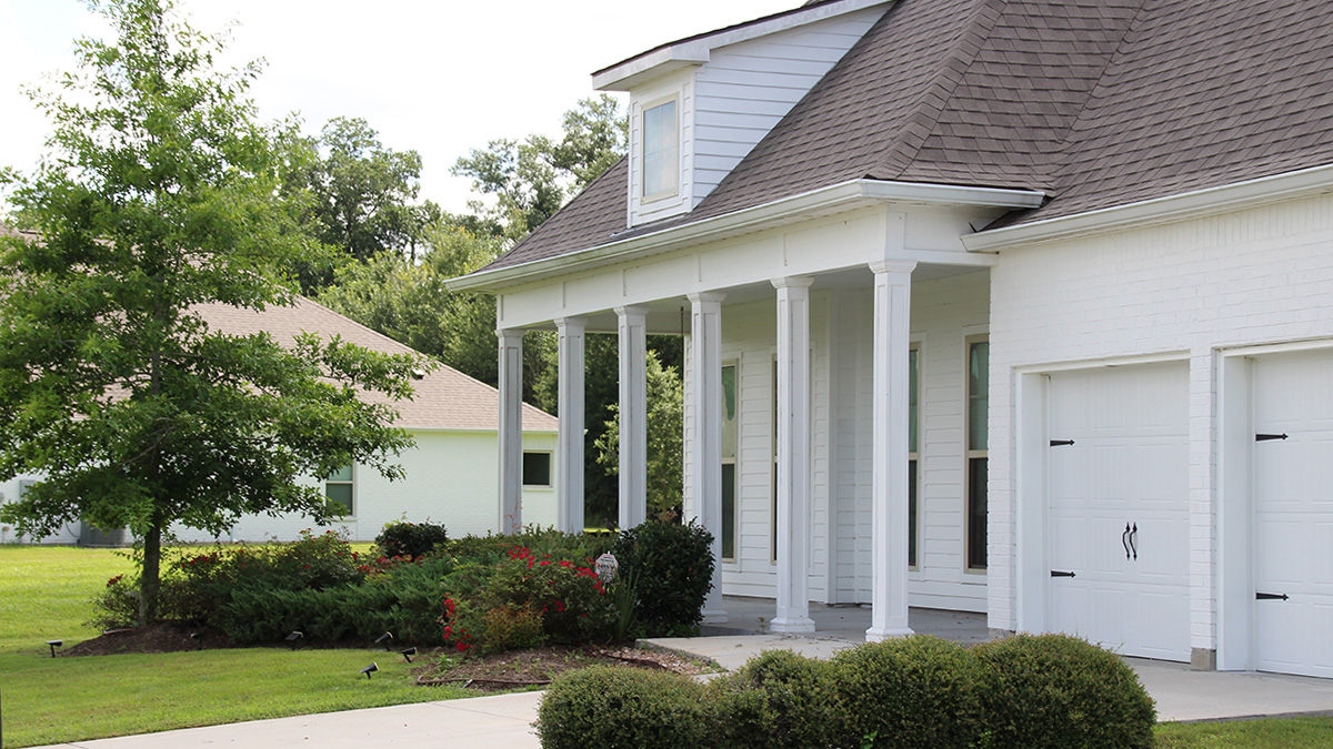 White two story home with white brick and white posts and two car garage