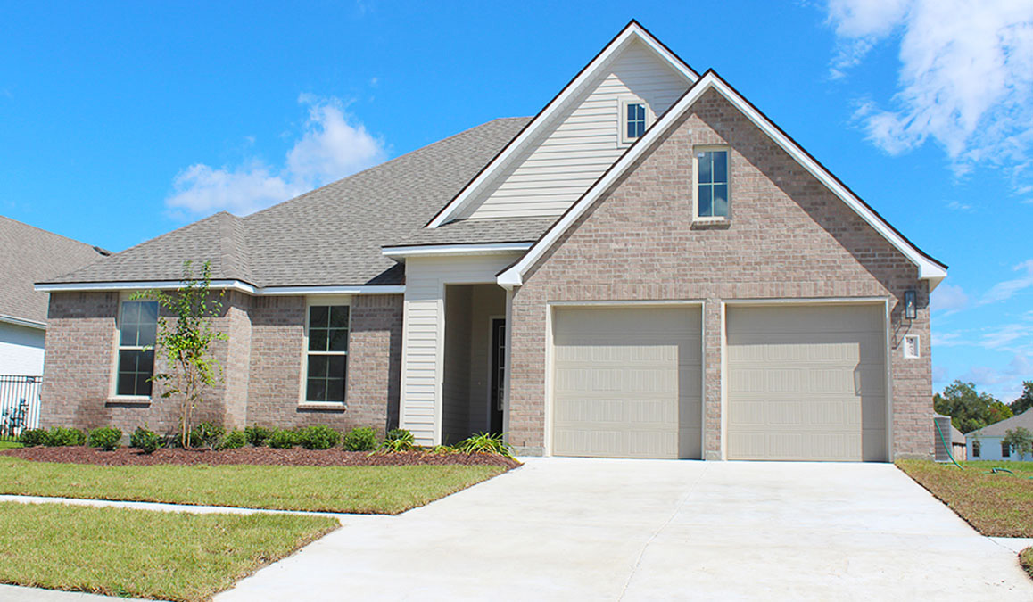 Single-story home with tan vinyl and brown brick. Black glass front door. and white trim.