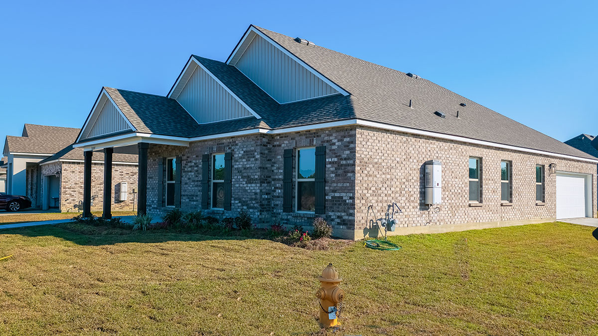 single-story home with grey brick and light gray vinyl siding with black shutters